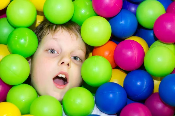 Niño acostado en una pila de bolas de colores —  Fotos de Stock