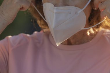 Gerçek bir kadın, Madrid, İspanya 'nın Etiro bölgesinde sokakta yürürken COVID-19 virüsünün diğer insanlara yayılmasını önlemek için koruyucu maskeyi nasıl takacağını gösteriyor..