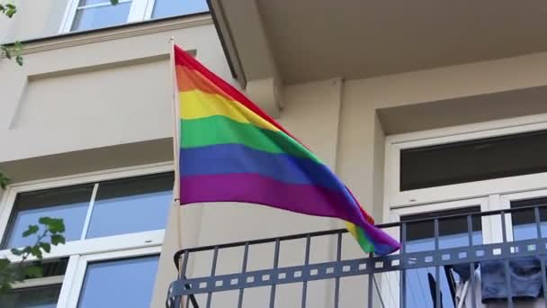 Lgbtコミュニティの旗が風になびく Lgbtコミュニティの旗はアパートのバルコニーに固定されています — ストック動画