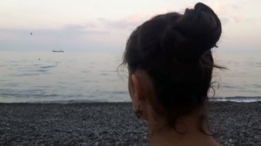 Denizin arka planında çekici bir kızın yakın plan portresi, kameraya bakıyor ve gülümsüyor. Mavi denizin arka planında genç güzel bir kızın portresi..