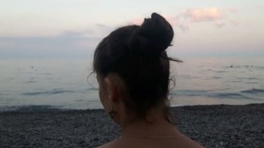 Denizin arka planında çekici bir kızın yakın plan portresi, kameraya bakıyor ve gülümsüyor. Mavi denizin arka planında genç güzel bir kızın portresi..