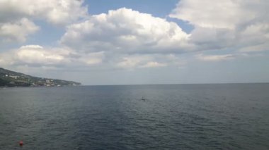 Denizde dalgalar bulutlu gökyüzünün arka planına karşı. Mavi deniz ve bulutların manzarası. Mavi denizin üzerinde beyaz bulutlar.