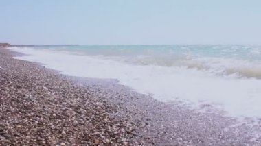 Fırtınalı deniz ve sahil manzarası. Deniz dalgaları çakıl bir sahilde yuvarlanıyor. Denizde fırtına.
