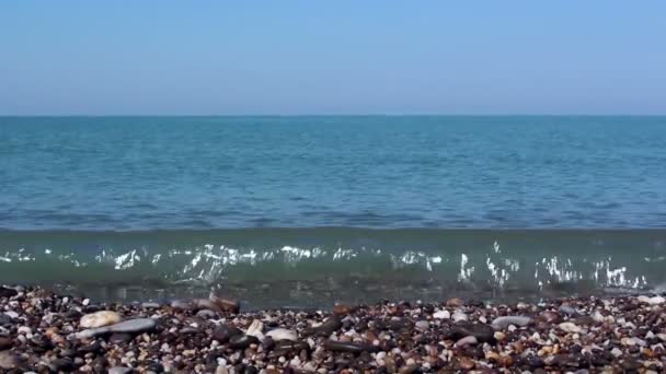 Vista al mar y a la costa rocosa, con guijarros marinos. Mar con agua azul clara.Surf marítimo en la costa rocosa . — Vídeos de Stock