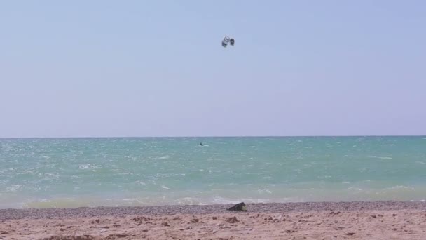 Kite surfista monta as ondas no mar azul. Uma vista do mar e um homem envolvido em kitesurf . — Vídeo de Stock