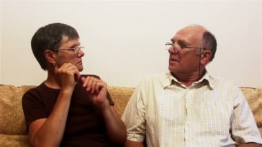 Çekici yetişkin kadın ve yetişkin erkek, görüş için gözlük denerler. Yaşlı bir çift evdeki kanepede oturur ve görüş için gözlük dener, birbirlerine danışırlar..