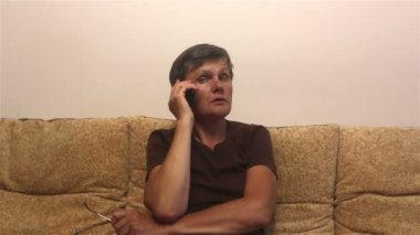Çekici yetişkin kadın akıllı telefonuyla bir telefon görüşmesi yapıyor, evdeki bir kanepede oturuyor. Bir kadın aktif olarak ailesiyle cep telefonuyla iletişim kuruyor, evdeki bir kanepede oturuyor..
