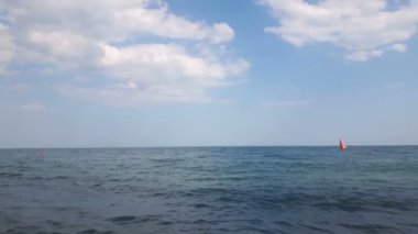 Mavi deniz ve bulutların manzarası. Denizde dalgalar bulutlu gökyüzünün arka planına karşı. Mavi denizin üzerinde beyaz bulutlar.