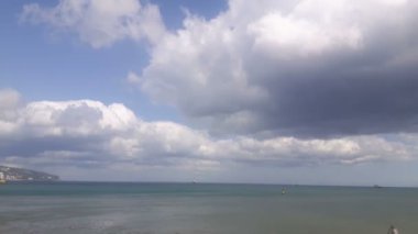 Mavi deniz ve bulutların manzarası. Denizde dalgalar bulutlu gökyüzünün arka planına karşı. Mavi denizin üzerinde beyaz bulutlar.