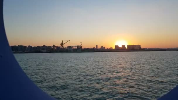 海洋和海港的日落 从邮轮的客舱欣赏海洋和城市 透过船的港口欣赏日落和海洋 — 图库视频影像