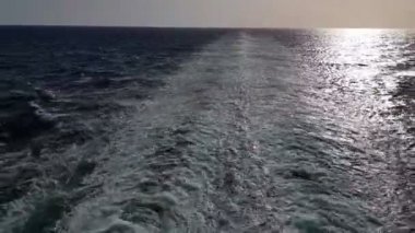 Gemiyi takip eden güçlü dalgalar. Geminin motorlarından izini sür. Mavi okyanusta yolcu gemisi yelken açar. Geminin kıç arkasında dalgalar. Gemiden gelen dalgalar ufka gidiyor..