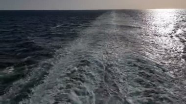 Gemiyi takip eden güçlü dalgalar. Geminin motorlarından izini sür. Mavi okyanusta yolcu gemisi yelken açar. Geminin kıç arkasında dalgalar. Gemiden gelen dalgalar ufka gidiyor..