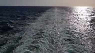 Gemiyi takip eden güçlü dalgalar. Geminin motorlarından izini sür. Mavi okyanusta yolcu gemisi yelken açar. Geminin kıç arkasında dalgalar. Gemiden gelen dalgalar ufka gidiyor..