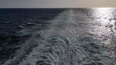 Gemiyi takip eden güçlü dalgalar. Geminin motorlarından izini sür. Mavi okyanusta yolcu gemisi yelken açar. Geminin kıç arkasında dalgalar. Gemiden gelen dalgalar ufka gidiyor..