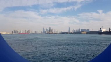 Güneşli bir günde deniz limanı ve mavi okyanus manzarası. Bir yolcu gemisinin porthole ile mavi okyanus görünümü. Ufukta gökdelenler ile deniz limanı ve şehir görünümü.