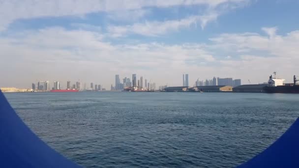 晴れた日の海港と青い海の眺め クルーズライナーのポートホールを通る青い海の眺め 地平線上に超高層ビルと都市の海の港と眺め — ストック動画