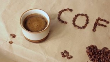 Bir fincan aromatik kahve kahve çekirdeklerinden ortaya konulan kahve kelimesi ile zanaat kağıda yerleştirilir. Yakın çekim.