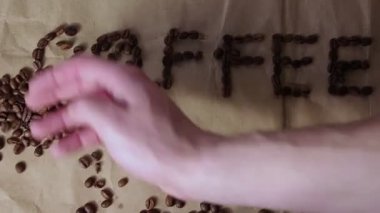 Erkek el yazısı kahve çekirdeklerini üzerine serper. Kahve. Yazı tahıldan yapılmış kahve..