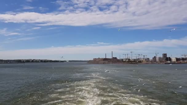 Vue du rivage et de l'océan depuis la poupe du navire.Vue des vagues suivant le navire par temps ensoleillé. Les mouettes volent derrière le navire .