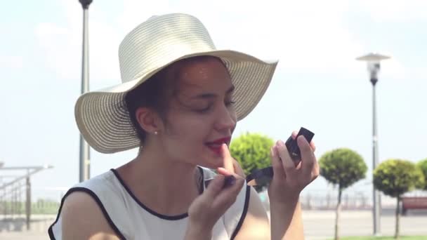 Μια Όμορφη Νεαρή Κοπέλα Λευκό Καπέλο Ζωγραφίζει Χείλη Της Κόκκινο — Αρχείο Βίντεο