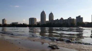 Nehir manzarası ve ufuktaki şehir. Yelkenli katamaranlarla ve teknelerle nehir manzarası.