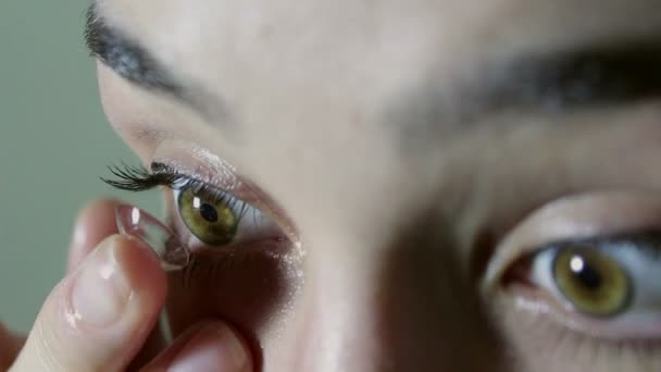 Belle jeune fille met une lentille de contact sur l'œil vert-brun. Yeux en gros plan. Portrait d'une jeune belle fille .