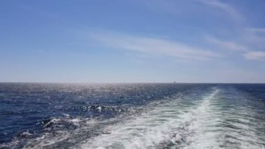 Gemiyi takip eden güçlü dalgalar. Geminin motorlarından izini sür. Mavi okyanusta yolcu gemisi yelken açar. Geminin kıç arkasında dalgalar. Gemiden gelen dalgalar ufka gidiyor..