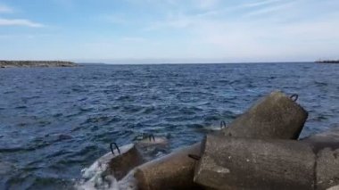 Dalgalar büyük taşlara vurur. Okyanus dalgaları limandaki taştan dalgalara vuruyor. Kıyıdaki okyanus ve taştan dalgaların manzarası.