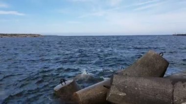 Dalgalar büyük taşlara vurur. Okyanus dalgaları limandaki taştan dalgalara vuruyor. Kıyıdaki okyanus ve taştan dalgaların manzarası.