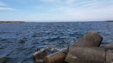Dalgalar büyük taşlara vurur. Okyanus dalgaları limandaki taştan dalgalara vuruyor. Kıyıdaki okyanus ve taştan dalgaların manzarası.