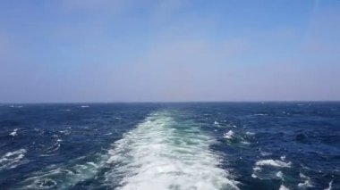 Gemiyi takip eden güçlü dalgalar. Geminin motorlarından izini sür. Mavi okyanusta yolcu gemisi yelken açar. Geminin kıç arkasında dalgalar. Gemiden gelen dalgalar ufka gidiyor..