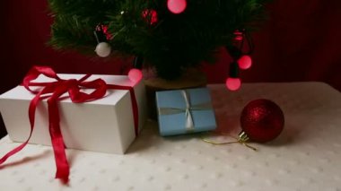 Renkli ışıkları, oyuncakları ve hediyeleri olan Noel ağaçları. Güzel ambalajlı yeni yıl hediyeleri oyuncaklar ve çelenklerle süslenmiş bir Noel ağacının altında yatıyor..