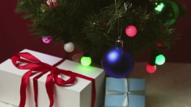 Renkli ışıkları, oyuncakları ve hediyeleri olan Noel ağaçları. Güzel ambalajlı yeni yıl hediyeleri oyuncaklar ve çelenklerle süslenmiş bir Noel ağacının altında yatıyor..