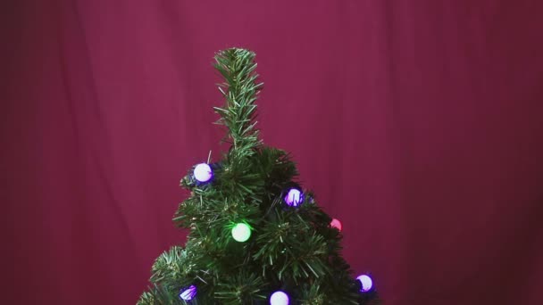 若い男が赤い光沢のあるボールでクリスマスツリーを飾る男の手は クリスマスツリー上の赤い光沢のあるボールを掛けます — ストック動画