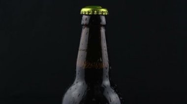  Yoğunlaşan damlalar arka planda bira şişesine akıyor. Bir sisli bira şişesi. Su bir şişe koyu biradan aşağı akar..