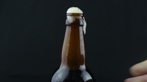 啤酒泡沫从烟雾弥漫的瓶子里流下来 泡沫流下一瓶深色啤酒 深色背景下的特写啤酒 — 图库视频影像