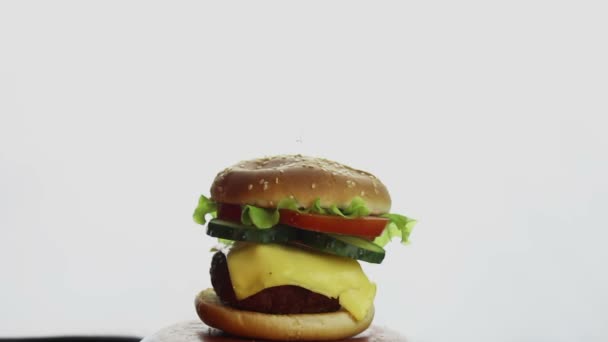 Les mains des hommes prennent un grand hamburger dans une assiette. Grand hamburger juteux avec escalope de bœuf, légumes frais et fromage à la crème. Burger gros plan sur fond blanc . — Video