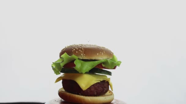 Mano maschile "allunga" l'hamburger mostrando gli ingredienti.Composizione di un hamburger di grandi dimensioni, gli ingredienti appesi singolarmente in aria. Le parti costitutive dell'hamburger. v — Video Stock