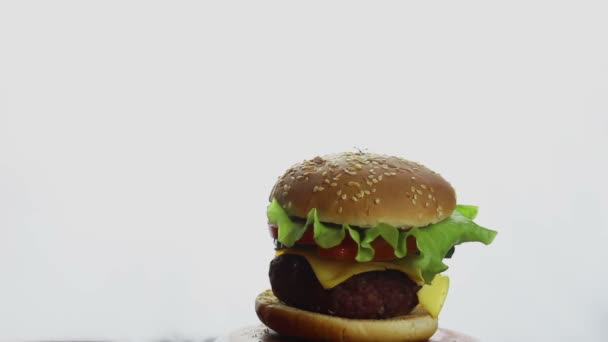Férfi kéz mutatja hüvelykujj fel a friss lédús burger. Nagy lédús burger marhahússal, friss zöldségekkel és olvadt sajttal. Gyorsétterem, magas kalóriatartalmú ételek. — Stock videók