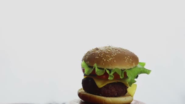 Mannelijke hand toont duim omhoog op verse sappige hamburger. Grote sappige hamburger met rundvlees, verse groenten en gesmolten kaas. Fast food, calorierijk voedsel. — Stockvideo