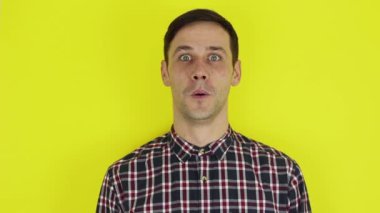 Close-up portrait of a young attractive guy, he laughs and looks at the camera. Portrait on a yellow background.