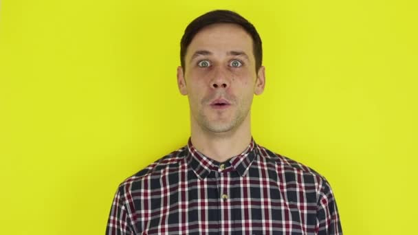 Close-up portrait of a young attractive guy, he laughs and looks at the camera. Portrait on a yellow background. — Stockvideo