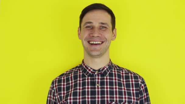 Closeup portrait of a young attractive guy, he is looking at the camera and smiling. Portrait on a yellow background. — Stok video