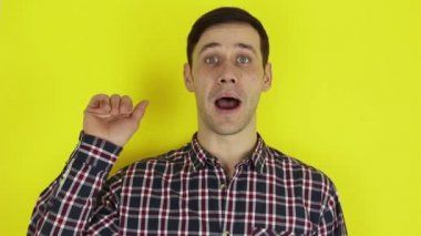Close up portrait of a young attractive guy, he is smiling and waving goodbye to his friends. Portrait on a yellow background.