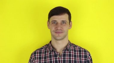A funny handsome guy says yes and nods affirmatively. Portrait on a yellow background.