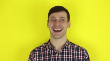 A funny handsome guy says yes, smiles and nods his head in the affirmative. Portrait on a yellow background.