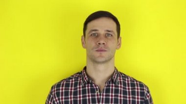 A funny handsome guy says yes, smiles and nods his head in the affirmative. Portrait on a yellow background.