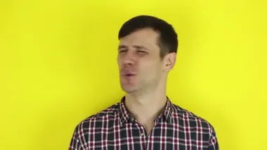 A funny handsome guy says no and shakes his head negatively. Portrait on a yellow background.