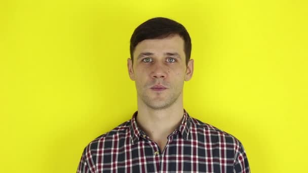 A funny handsome guy says yes and nods affirmatively. Portrait on a yellow background. — Stock videók