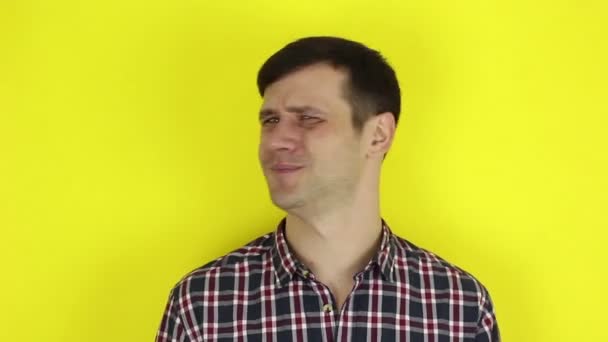 A funny handsome guy says no and shakes his head negatively. Portrait on a yellow background. — Stockvideo